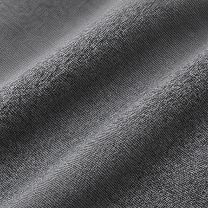 A close-up of dark gray ribbed knit fabric with soft diagonal folds showing the texture and weave.