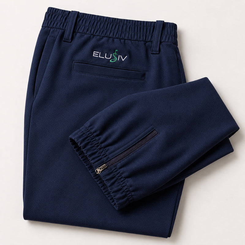 A pair of navy blue athletic golf jogger pants folded neatly on a light beige background. The pants feature an elastic waistband, a zippered pocket on the left leg, and the brand name 'ELUSIV' embroidered in white and green above the back left pocket.